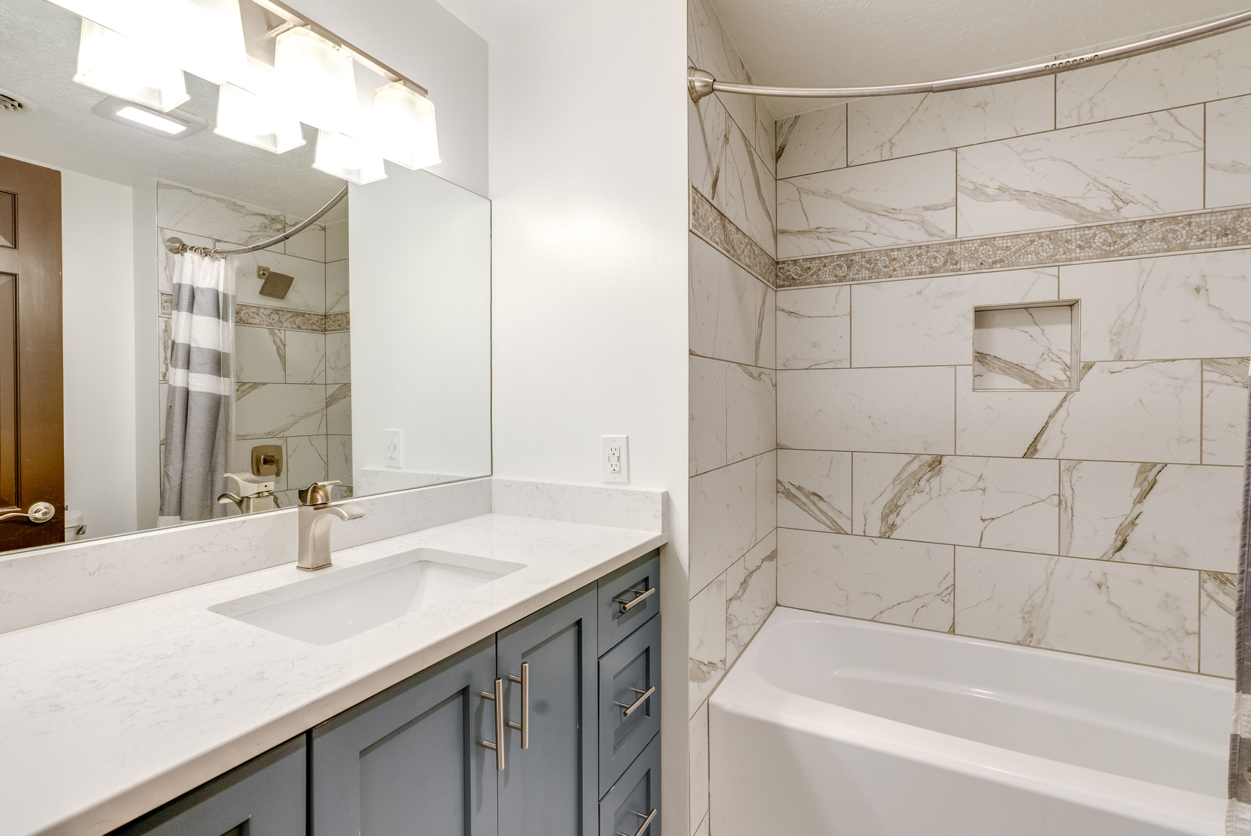 primary bathroom with custom shower tiles, molding and lighting