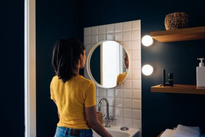 Young woman in front of wall mirror in a remodeled bathroom.